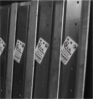 Industrial metal cutting blades stacked vertically with manufacturer labels in a workshop setting